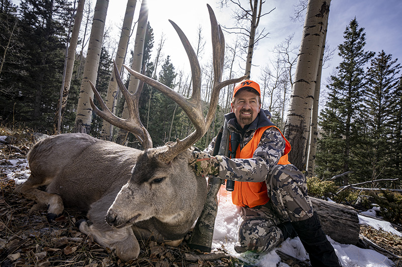 man with giant buck in woods